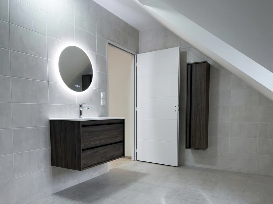 Salle de bain moderne sous combles, avec meuble vasque suspendu 3 tiroirs finition bois foncé, vasque céramique encastrée, robinet mitigeur chromé