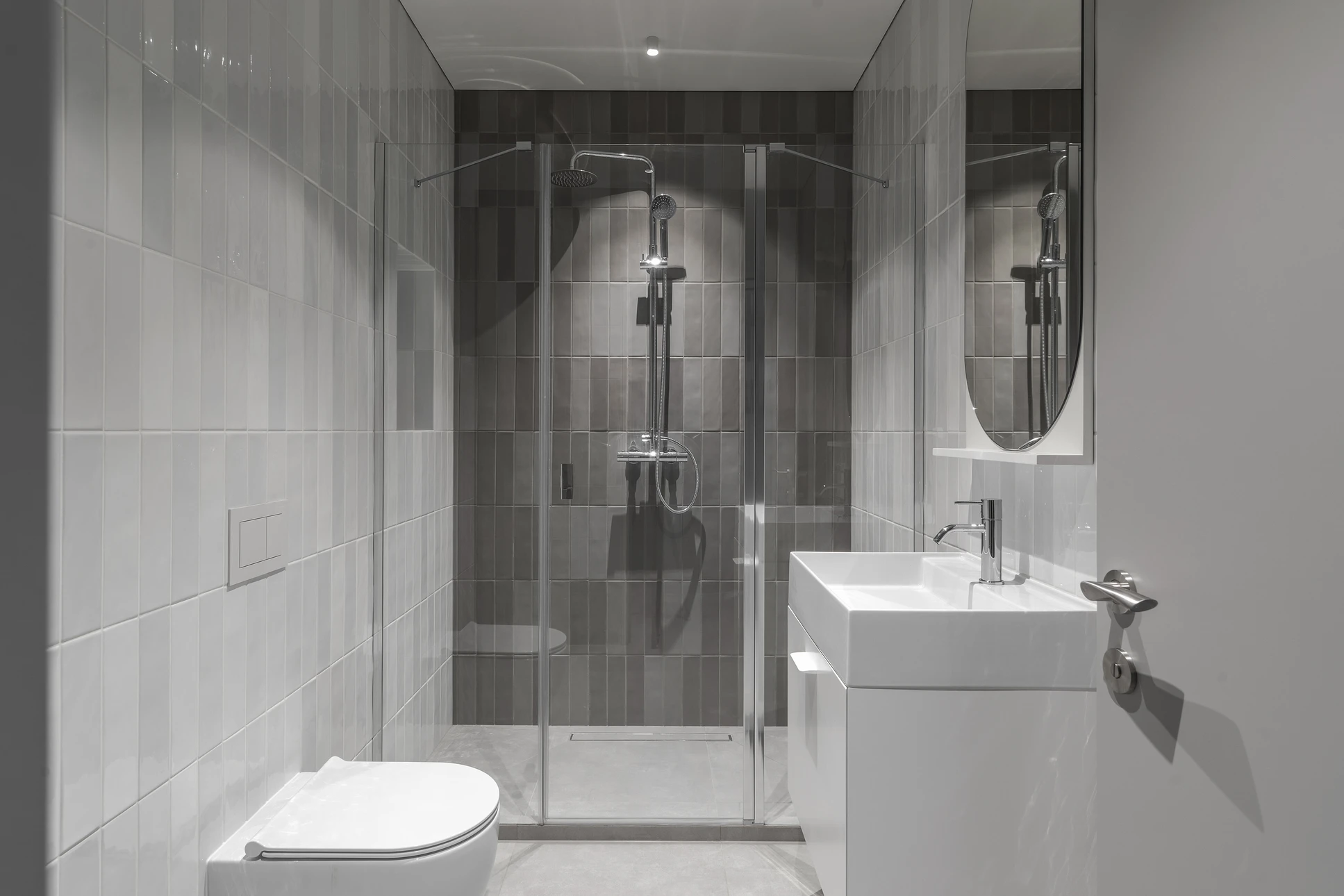 Salle de bain moderne compacte avec douche à l'italienne vitrée, WC suspendu et vasque rectangulaire sur meuble blanc