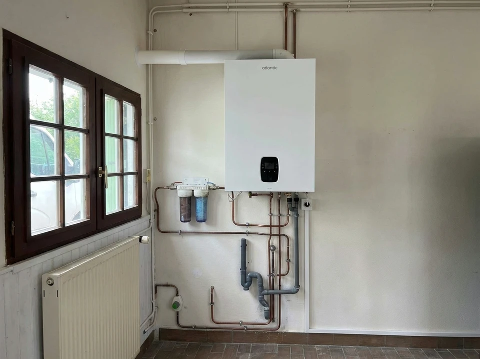 Homme en tenue de travail ajustant un radiateur blanc dans un intérieur résidentiel près d'une fenêtre